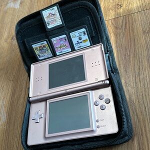 Used pink DS lite. No charging cord. With four games and pink carry case.
